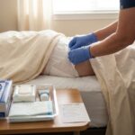 Caregiver adjusting adult brief at bedside with supplies tray visible conveying dignified in-home bedside care